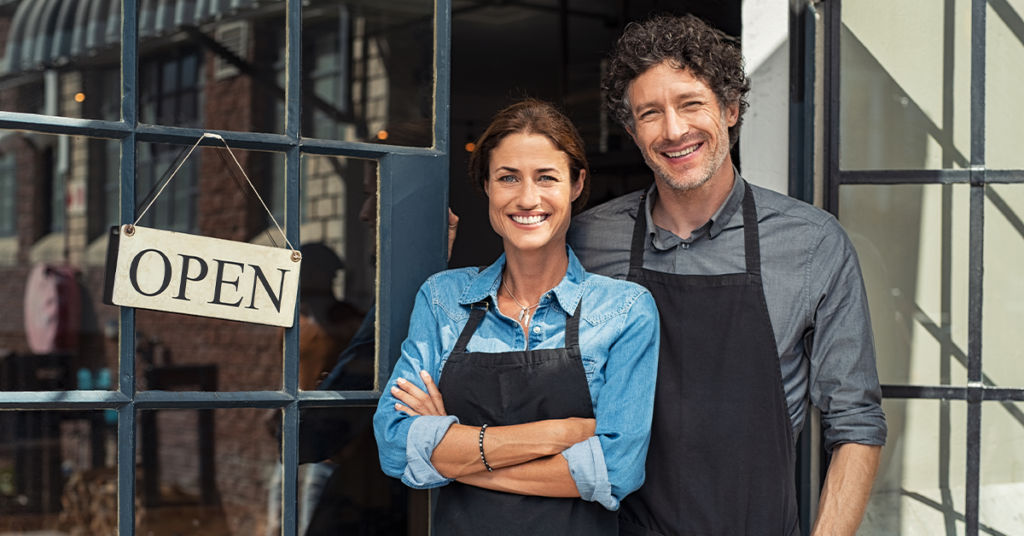 A woman and man standing in front of an open small business