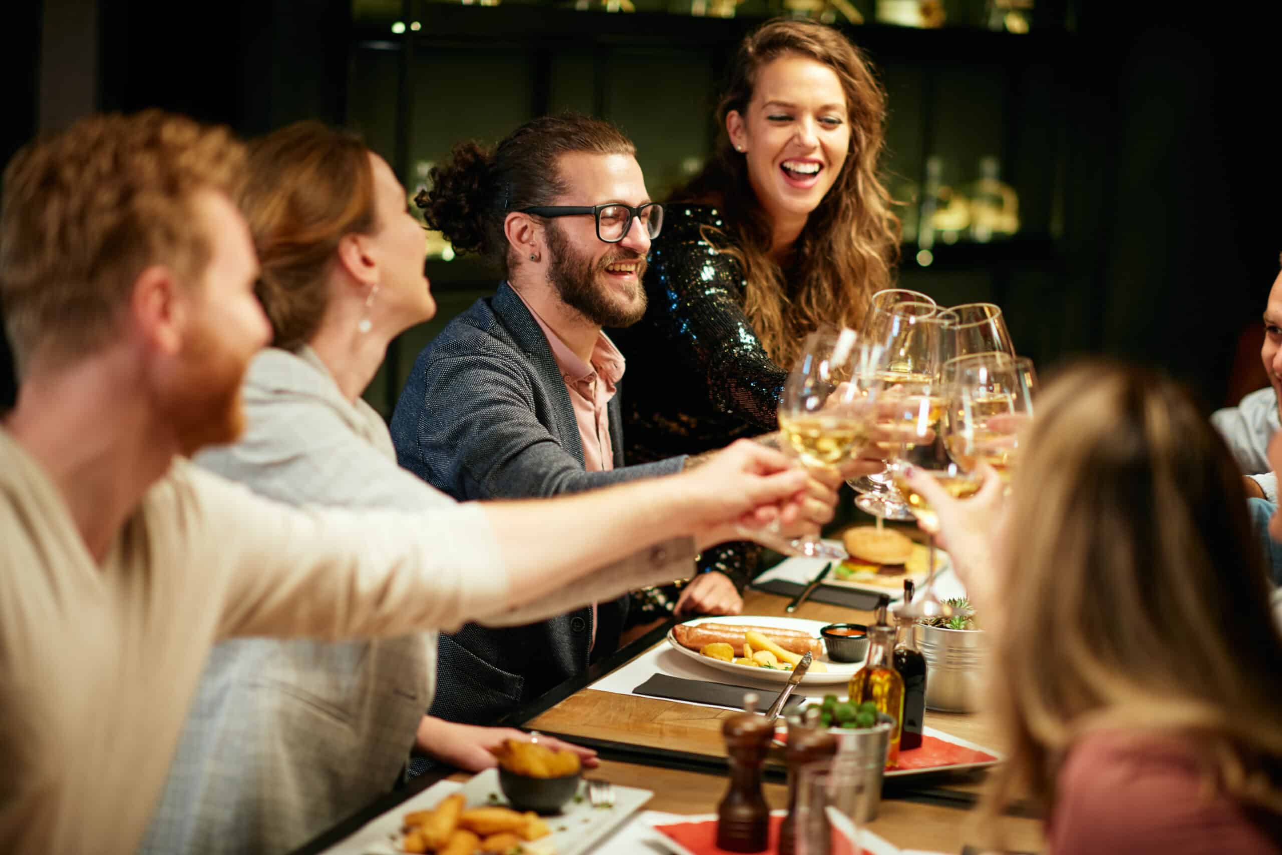 Friends toasting with wine at a lively restaurant dinner.